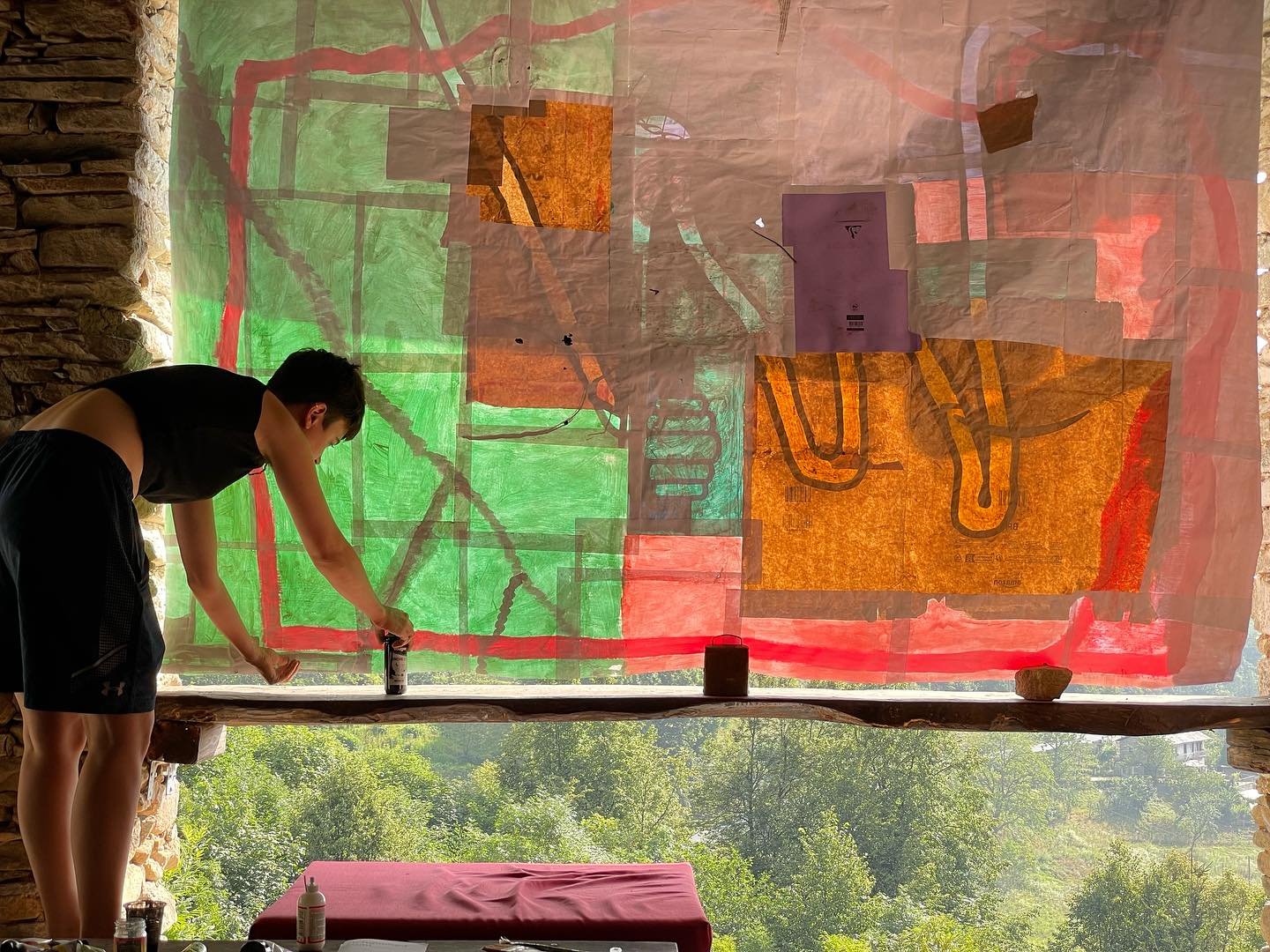An artist working on a large painting on translucent paper