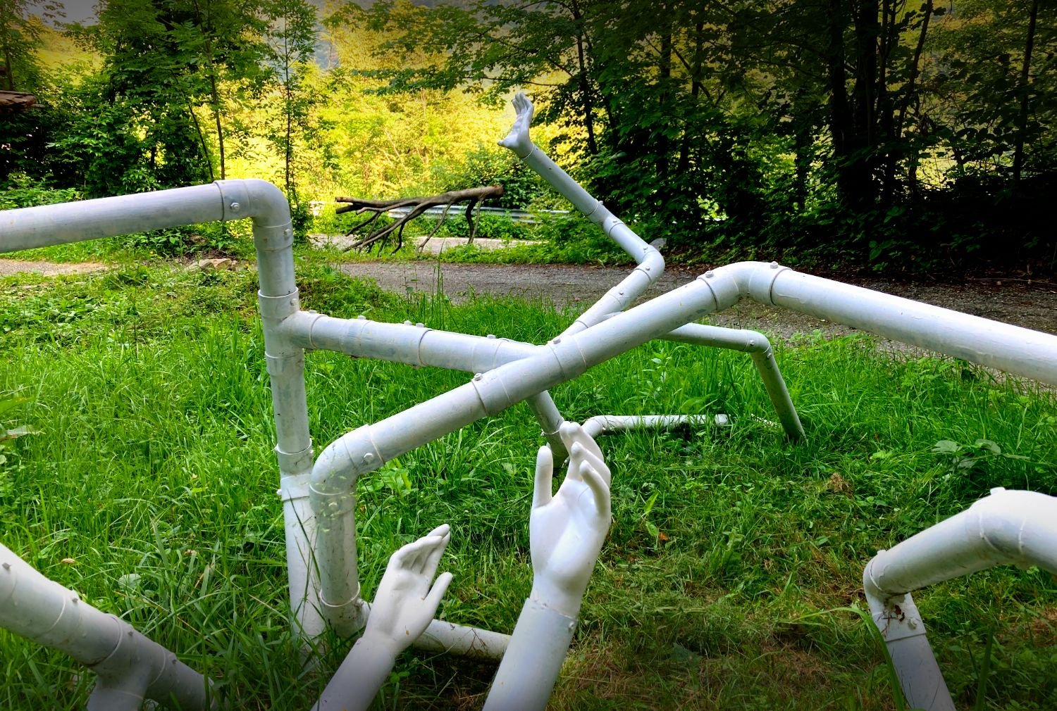 A sculpture of white pipes and hands in the meadow